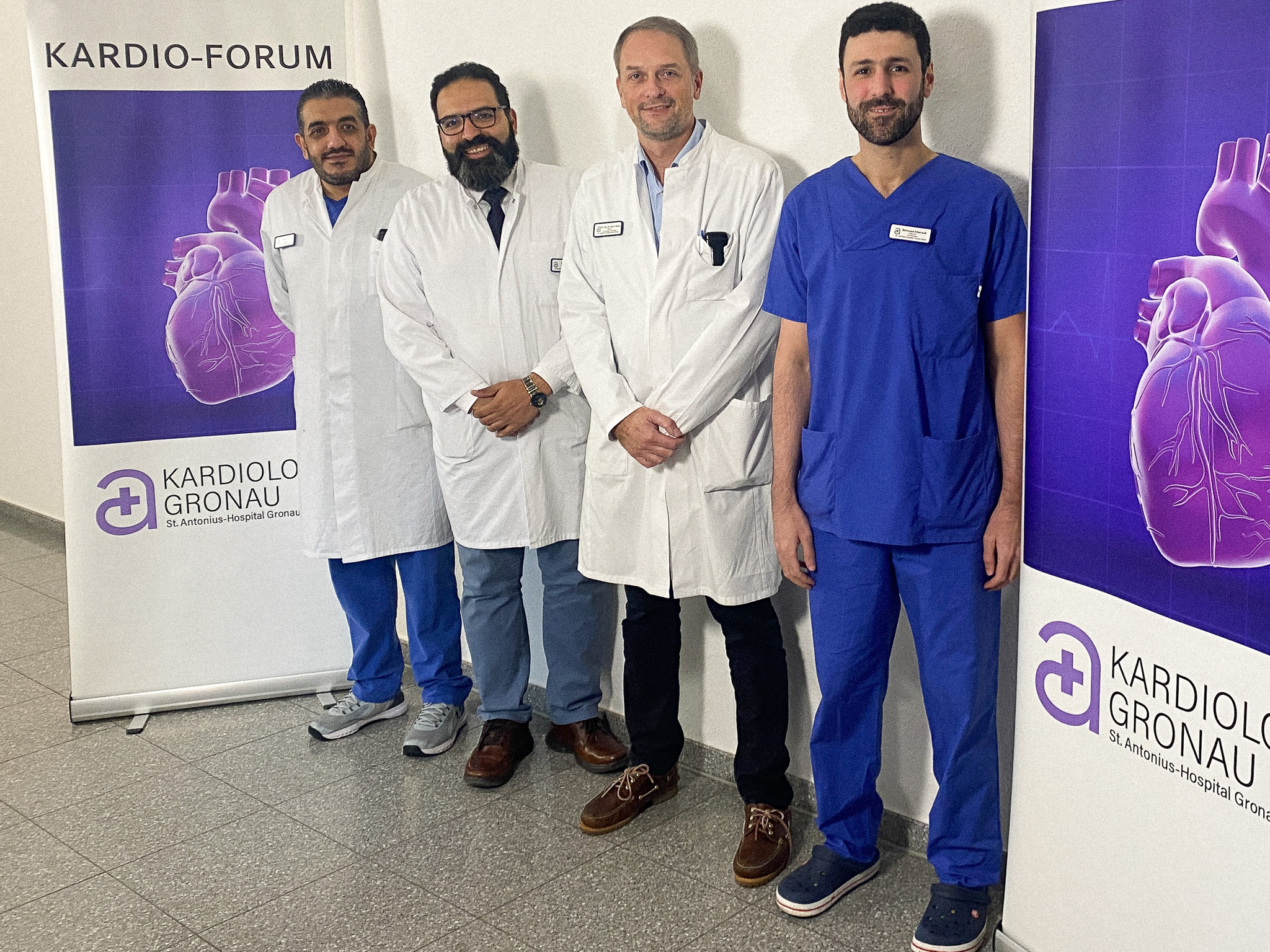 Von links: Wael El Eit, Sherif Omar, Dr. med. Alexander Samol und Mohamed Elbaroudy. Die Ärzte der kardiologischen Klinik stehen von links nach rechts an einer Wand, eingerahmt von zwei Aufstellern zum Kardio-Forum: