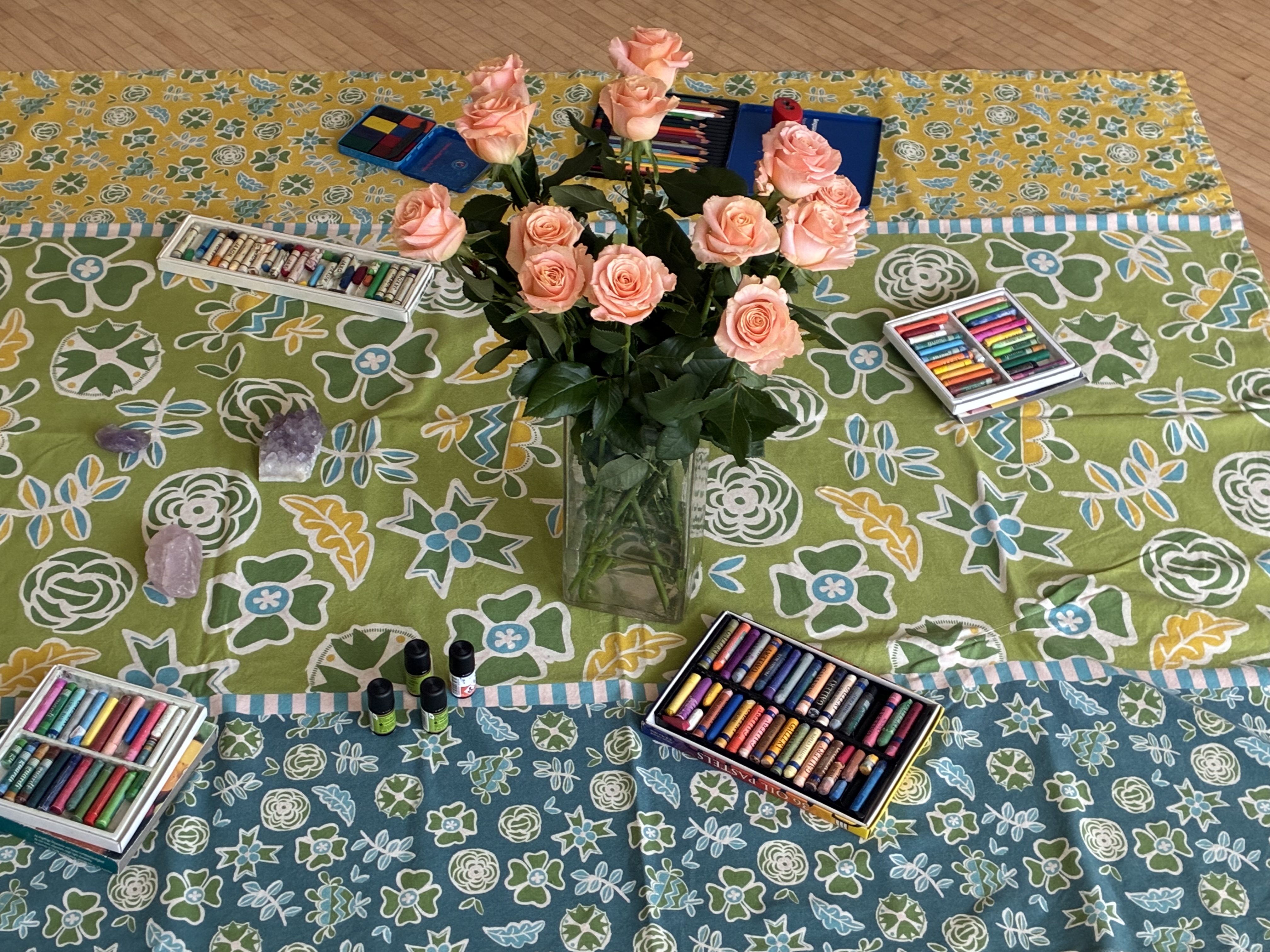 Das Stimmungsbild vom Seminar zeigt einen zartrosafarbenen Blumenstrauß in der Vase, Buntstifte auf einer Decke. 