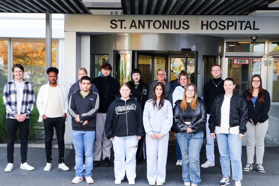 Die Auszubildenden stehen vor dem Haupteingang des St. Antonius Hospitals und lächeln in die Kamera. 