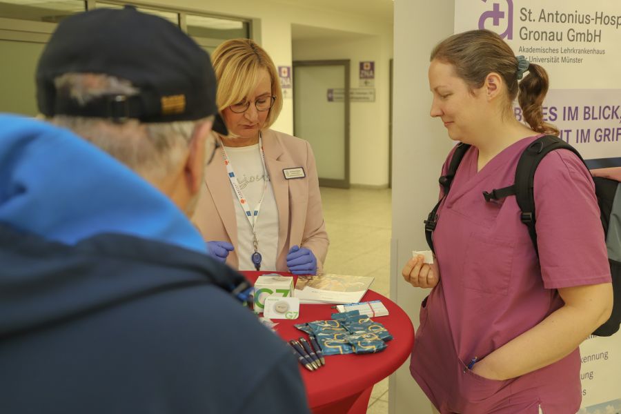 Eine Mitarbeiterin und ein Besucher (von hinten) lassen sich von Diabetesberaterin Andrea Klesse die Blutzuckerwerte bestimmen. 