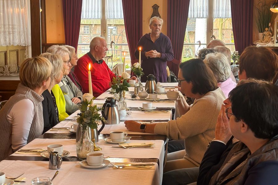 Die Ehrenämtler des Katharinenstfts sitzen am Esstisch, während Hausleiterin Marion van der Wals sie stehend begrüßt.  