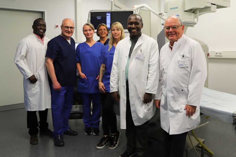 Die beiden Ärzte aus Tansania neben Dr. Jörg Zinke und weiteren OP-Mitarbeiterinnen in einem Behandlungszimmer. 