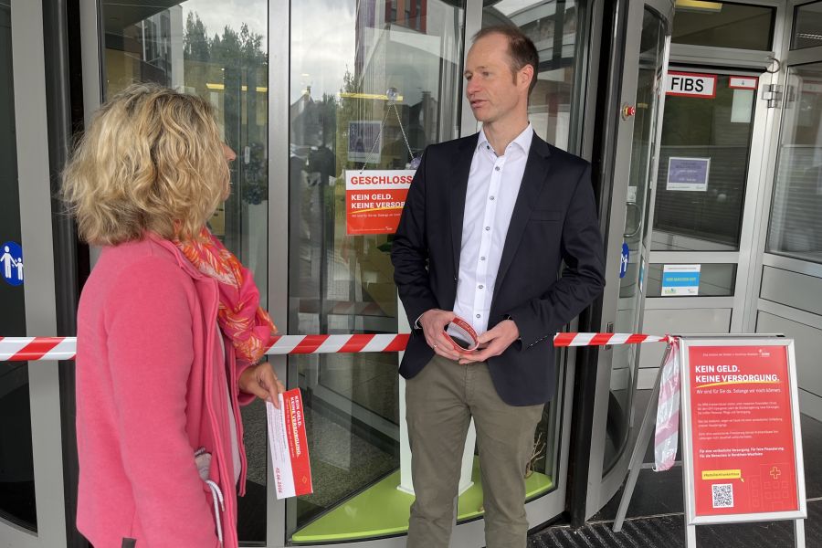 Geschäftsführer Jens Breer vor dem Haupteingang des St. Antonius-Hospital Gronau im Gespräch mit einer Besucherin.